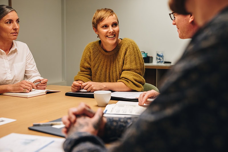 Mennesker sidder ved bord til workshop om feedbackkultur på arbejdspladsen.