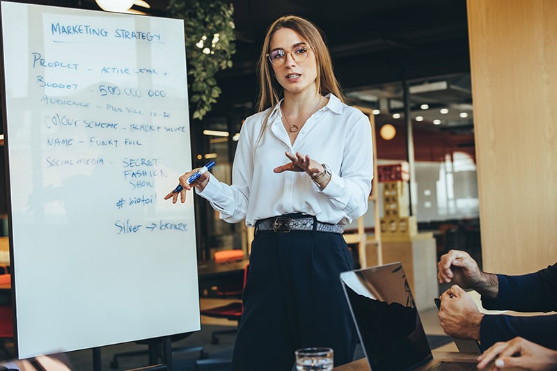 Chef med en temposættende ledelsesstil præsenterer for medarbejdere.